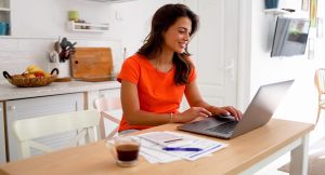 Mulher trabalhando em seu computador na cozinha.