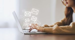 Um notebook aberto com ilustrações de e-mails saindo da tela.