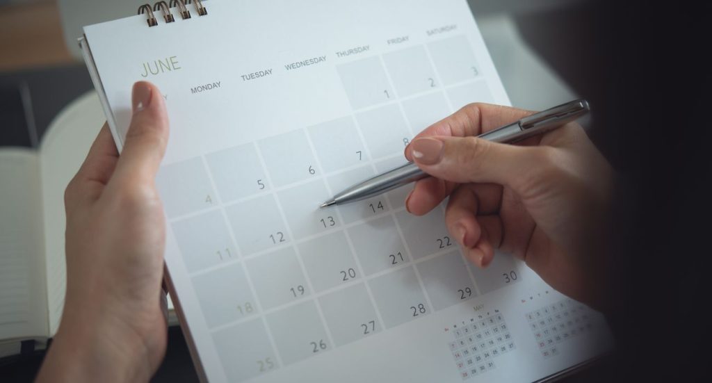 Um calendário sendo preenchido com uma caneta.