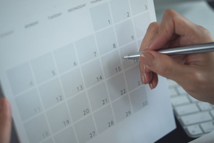 Um calendário sendo preenchido por uma caneta.