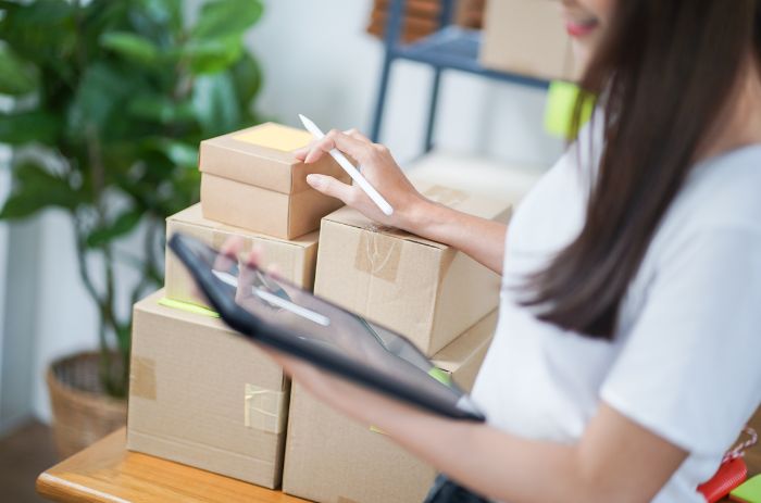 Mulher fazendo anotações sobre a logística dos próximos produtos que precisa enviar.