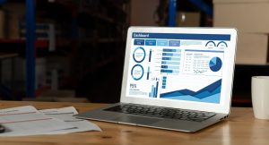 Computador sobre uma mesa, apresentando relatórios de uma ferramenta de BI.