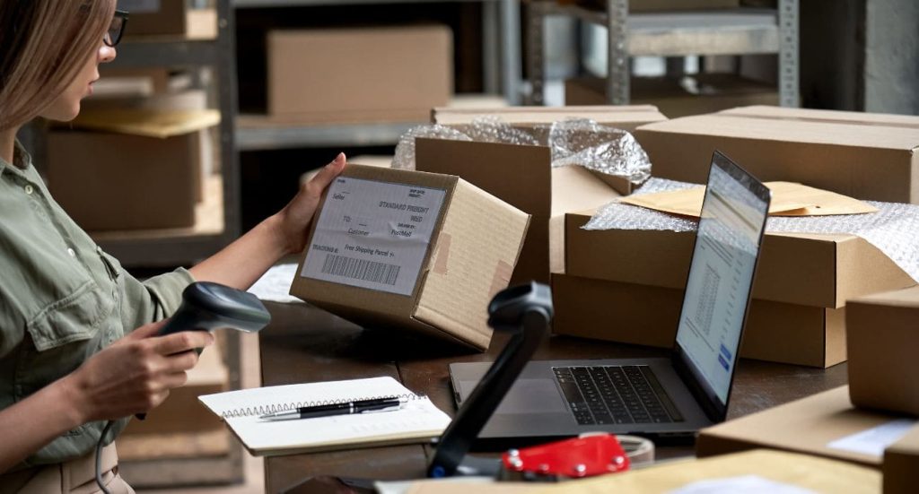 Mulher catalogando produto para enviar pela transportadora.