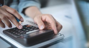 Homem utilizando calculadora para fazer planejamento tributário.