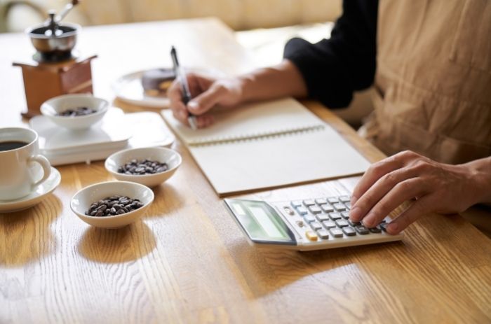 Mulher fazendo contas para entender qual seu custo de aquisição de produto.