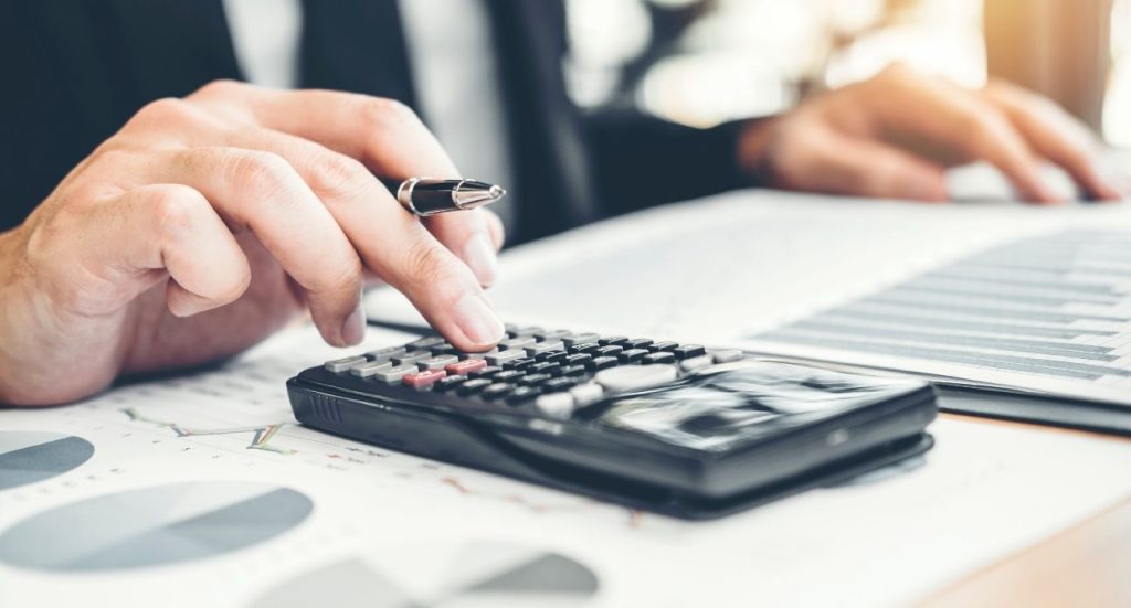 Empresário utilizando calculadora para descobrir seu custo de aquisição.