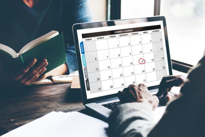 Duas pessoas no escritório com notebook aberto em um calendário
