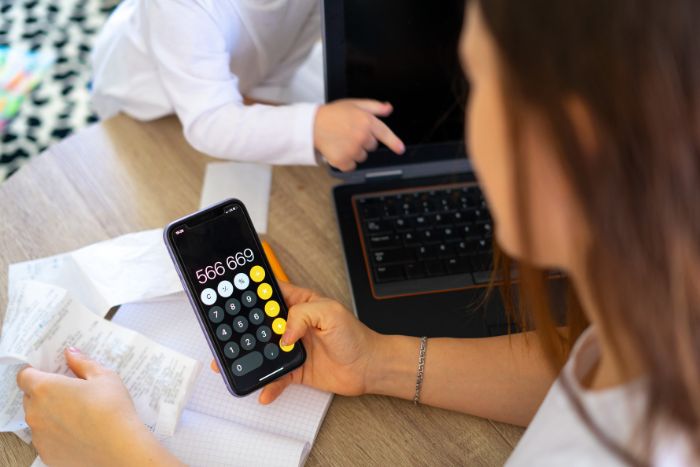 mulher fazendo cálculos no celular.